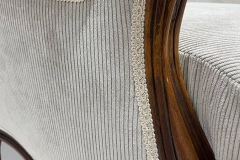 Dettaglio del bracciolo di una poltrona classica restaurata con tessuto a coste beige e rifinitura in passamaneria intrecciata artigianale.